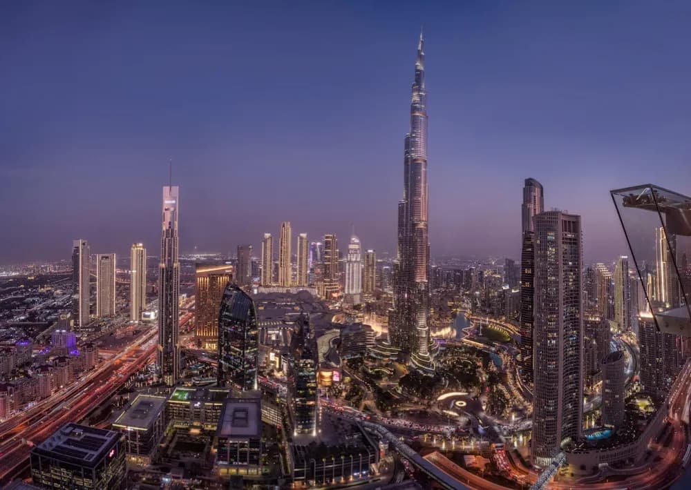 A dense city skyline at dusk, lit from the streets below.