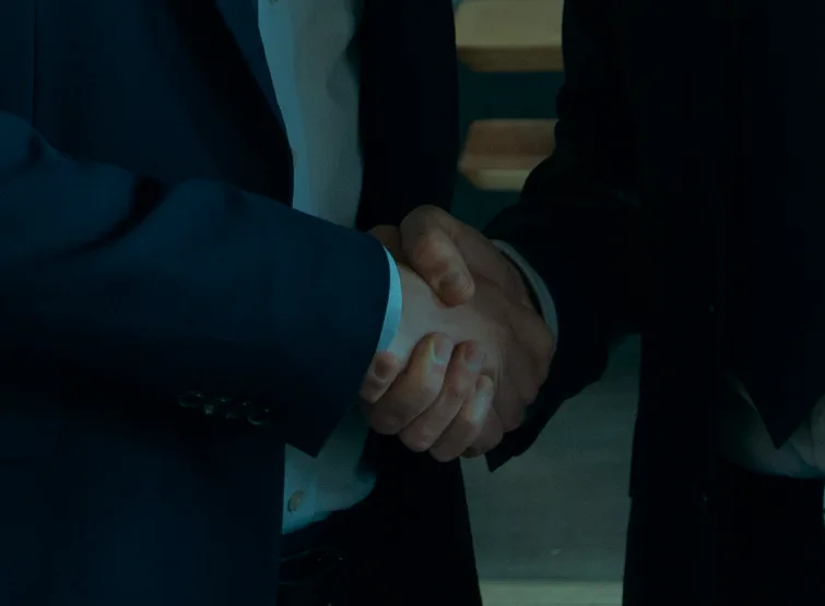 Two people in suits shaking hands.