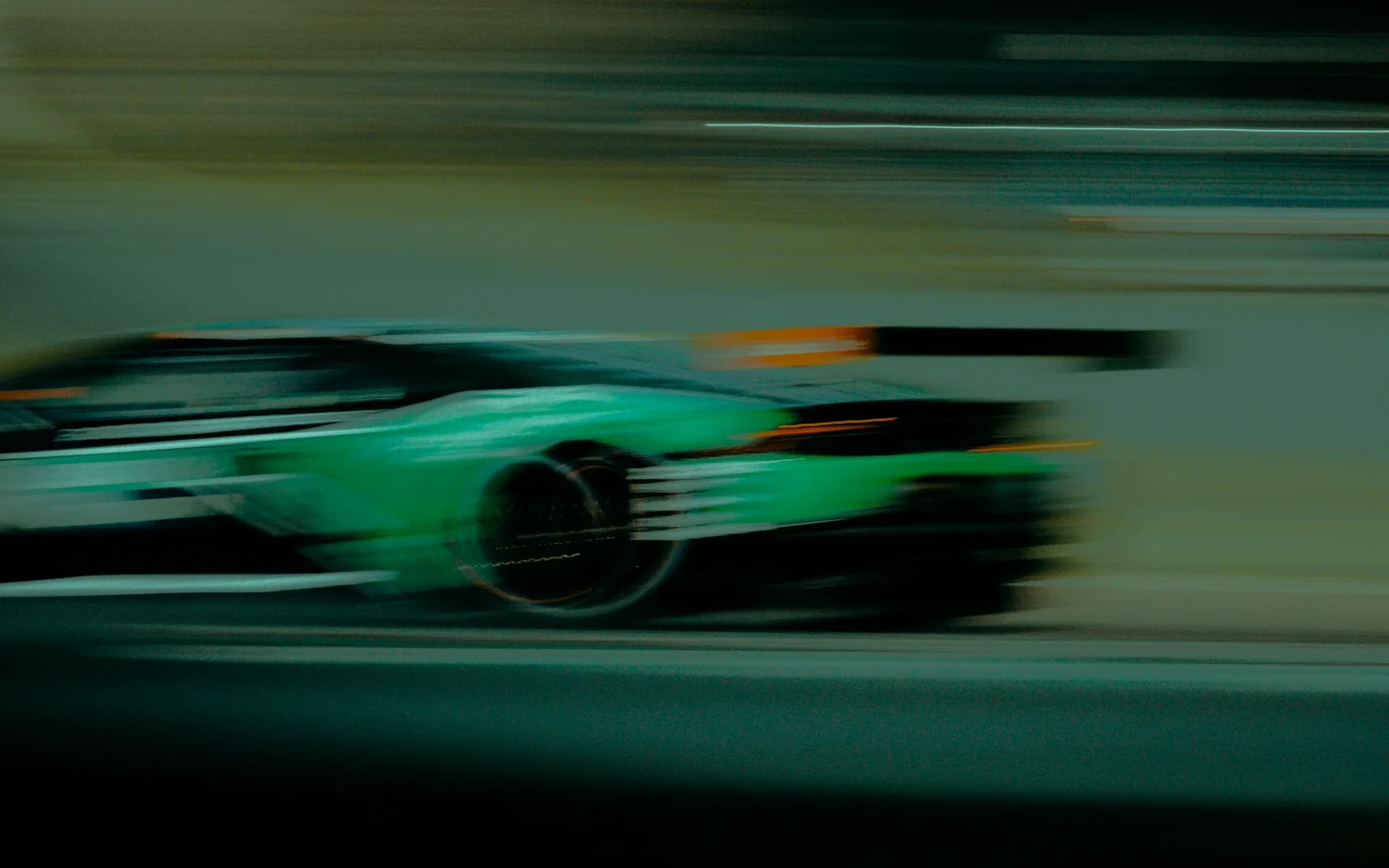 A green racing car at speed, the track behind it blurred.
