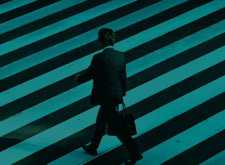 A person in a suit crossing a striped pedestrian crossing.