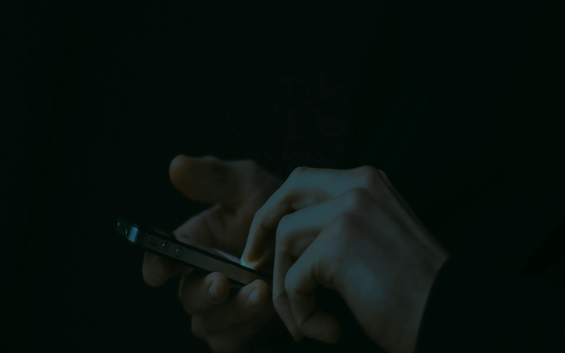 A person holding a phone in a dark room.