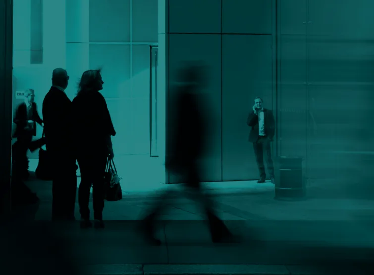 People walking through a glass office lobby.