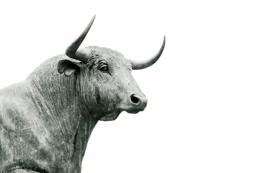 A bull statue in profile against a plain ground.