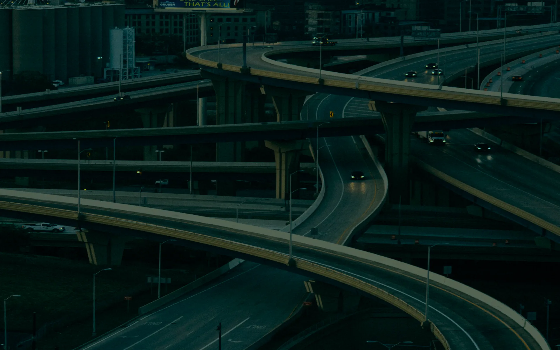 A stacked motorway interchange at dusk, seen from above.