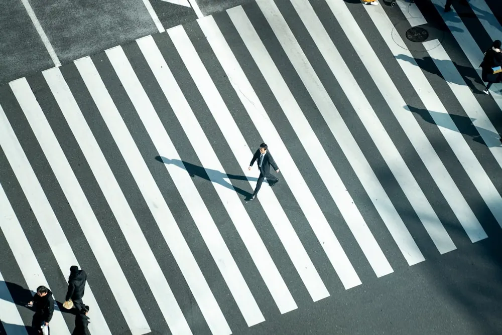 Two people crossing a striped pavement, seen from above.