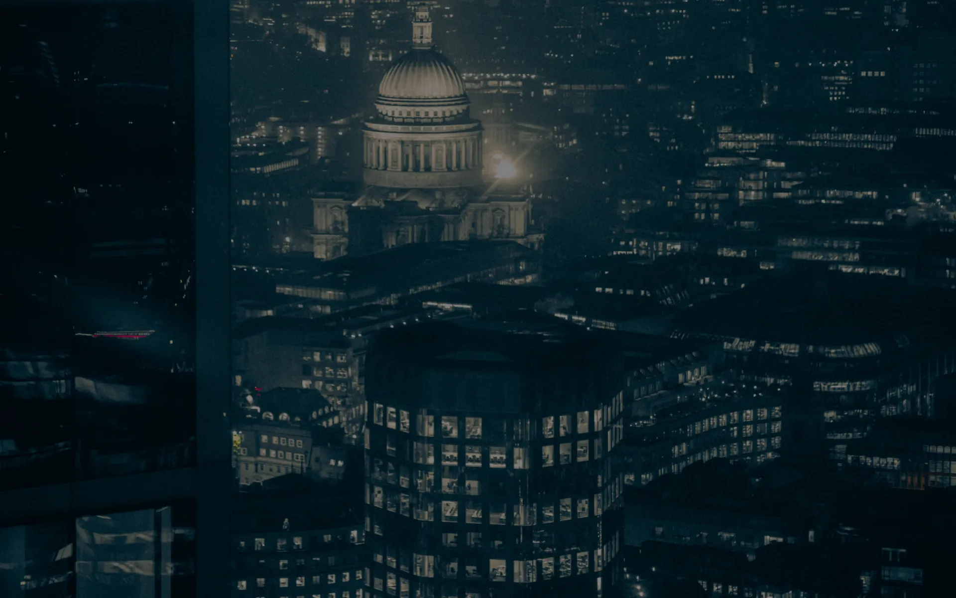 A lit city at night, seen from a tower window.