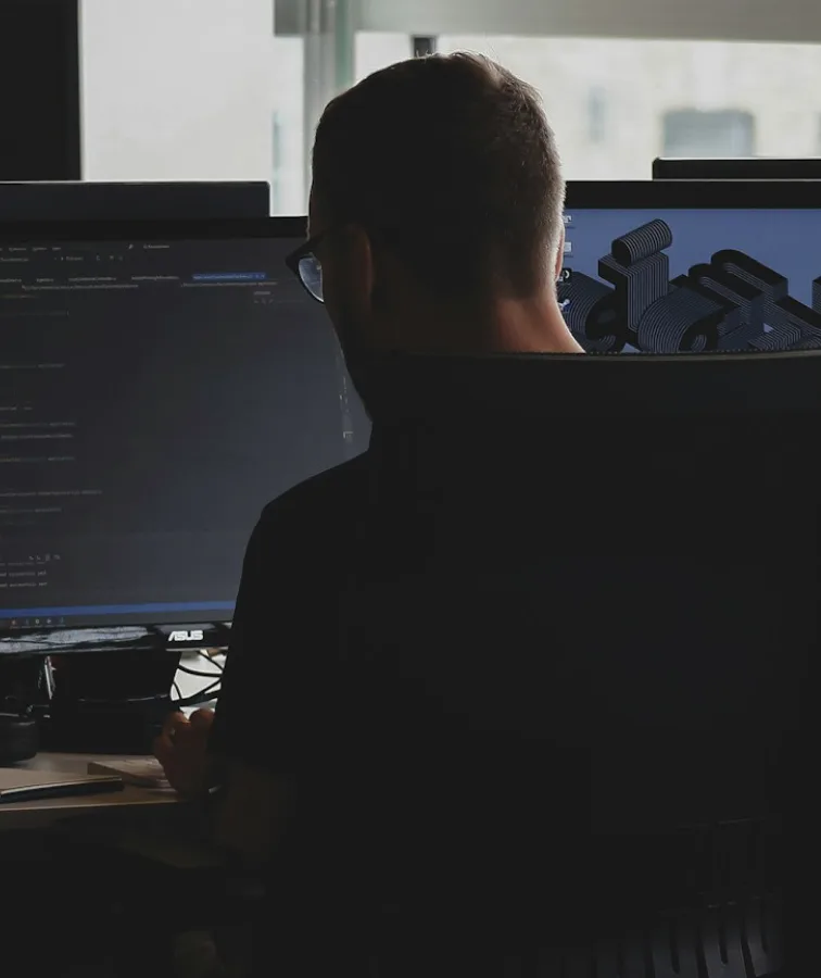 A developer at a desk of screens, seen from behind.