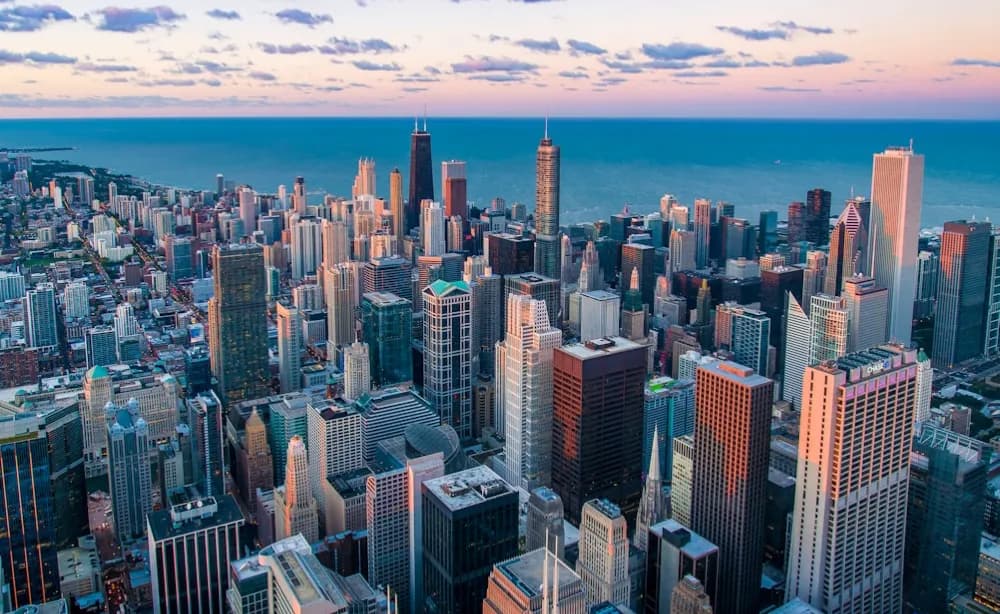 A lakeside city skyline at dusk, seen from above.