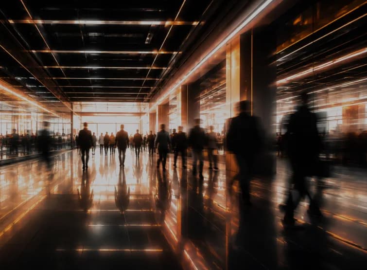 People crossing a lit concourse, caught in a long exposure.