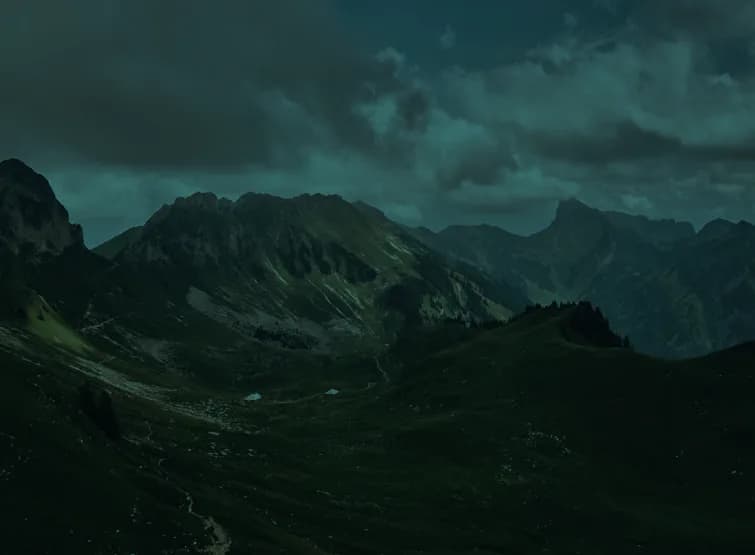A green mountain valley under a broken cloud layer.