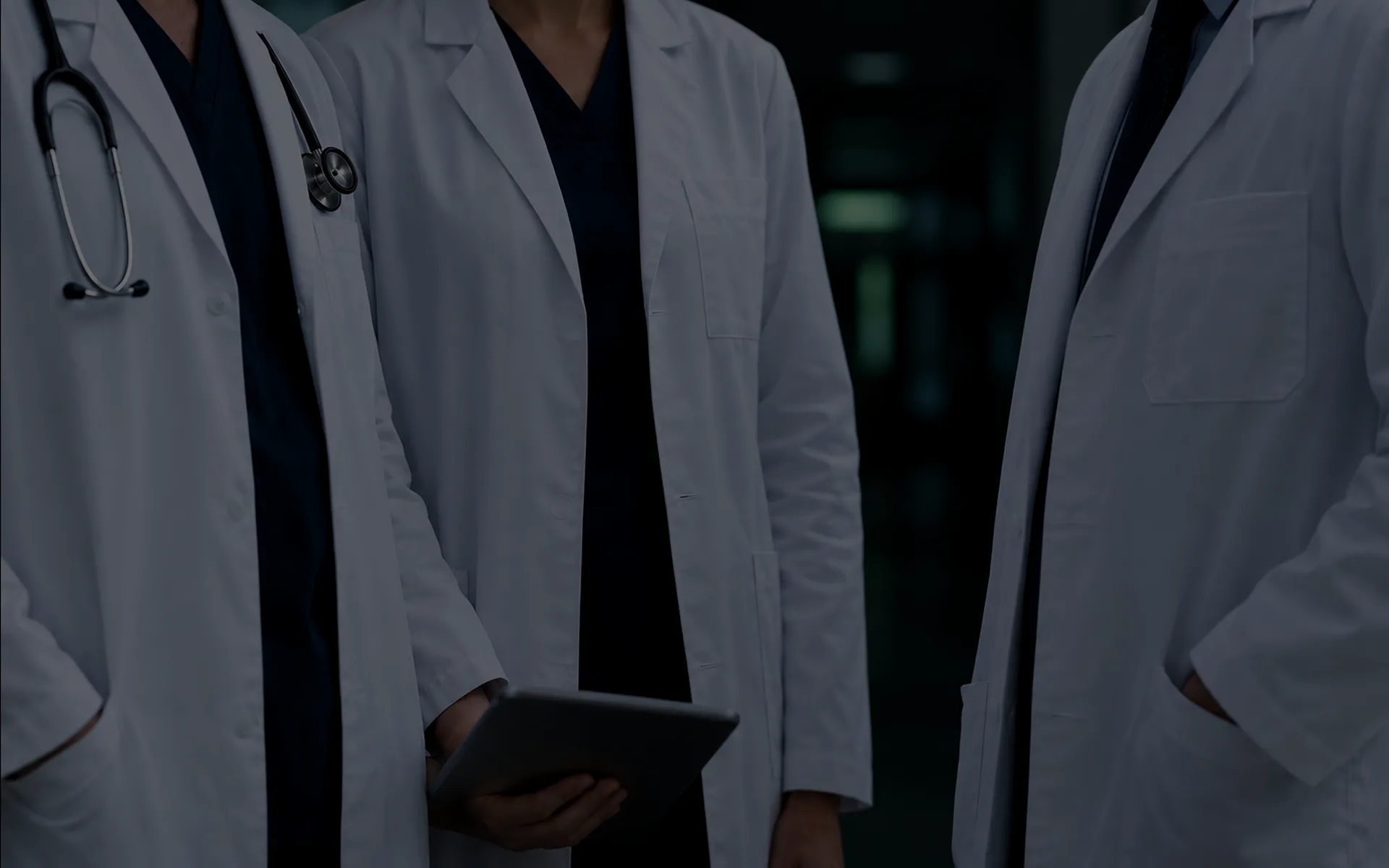 Three doctors in white coats stand together, seen from the shoulders down.
