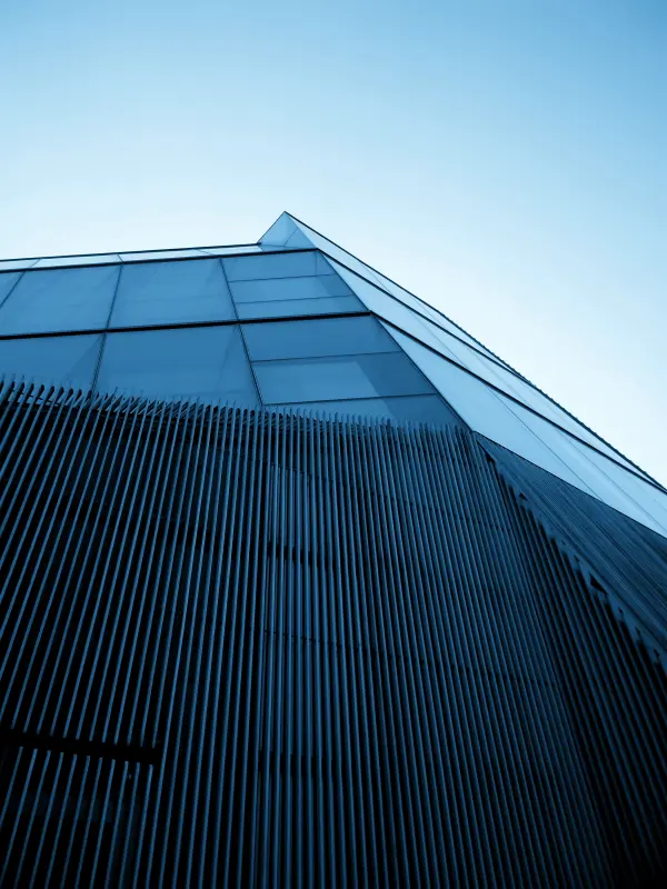 The corner of a glass and metal tower, seen from below.