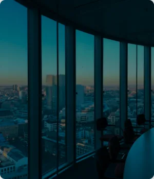 Curved office windows show a city skyline at dusk.