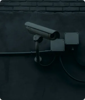 A security camera and junction boxes on a wall.