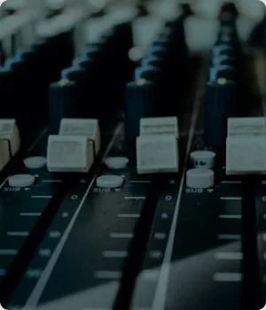 Close view of faders and knobs on an audio mixer.